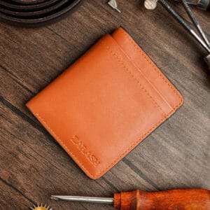 Brown leather wallet on a wooden surface with tools around