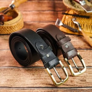 Two leather belts with gold buckles on a wooden surface.