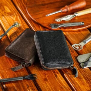 Black leather zippered case on a wooden surface with tools in the background
